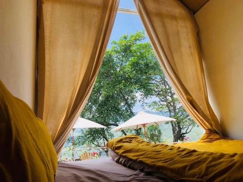 Cette chambre comprend 2 lits et une fenêtre avec des parasols. dans l'établissement Retro Khe Sanh, à Lao Bao