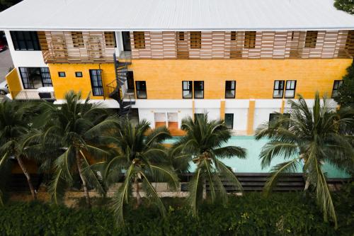 a building with a swimming pool and palm trees at Book a Bed Poshtel - SHA Plus in Phuket Town