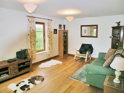 a living room with a green couch and a dog laying on the floor at Milton Byre in Rothesay