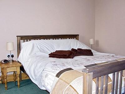 a bed with white sheets and brown pillows on it at The Old Stables in West Ashby