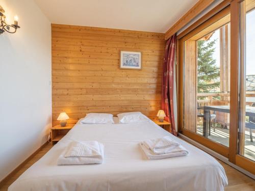 une chambre avec un lit et une grande fenêtre dans l'établissement Appartement au centre de la station avec balcon dans chalet, animaux acceptés - FR-1-645-45, à Huez