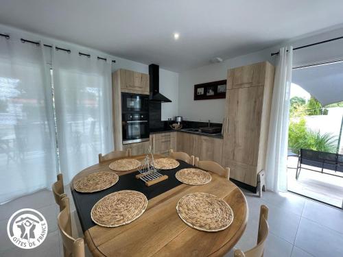 une table de salle à manger avec des chaises et une cuisine dans l'établissement Maison neuve en Vendée, 3 chambres, proche véloroute et océan, wifi, terrasses, tout inclus. - FR-1-426-542, à Beauvoir-sur-Mer