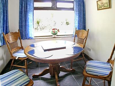 a table and chairs in a room with a window at Coombe End Cottage in Carnbrea