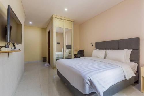 a bedroom with a large white bed and a television at Victoria Villa Seminyak in Seminyak