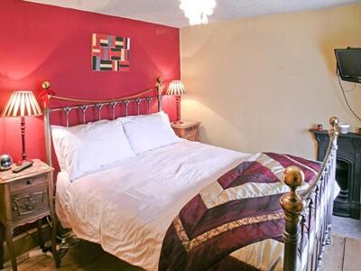 a bedroom with a bed with a red wall at Rustic Cottage in Bowness-on-Windermere