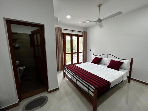 莫拉圖瓦的住宿－Bolgoda Lake Villa，一间卧室配有一张带红色枕头的床和一扇窗户