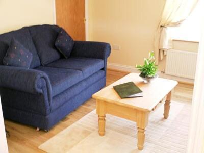 Sala de estar con sofá azul y mesa de centro en Barley Cottage - W40837, en Horsford