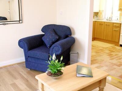 Sala de estar con silla azul y mesa de centro en Barley Cottage - W40837, en Horsford
