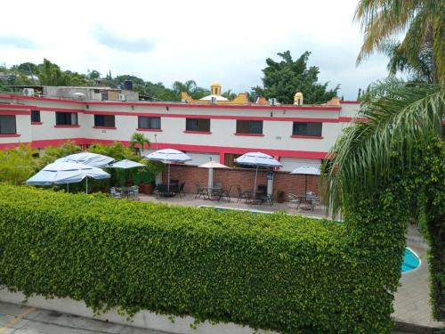 een gebouw met tafels en parasols ervoor bij Hotel Parador del Rey in Temixco