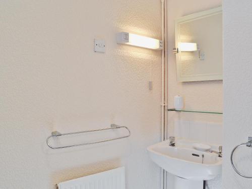 a bathroom with a sink and a toilet and a mirror at Dairy Cottage - 28344 in Staintondale