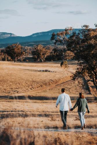 a man and woman walking through a field at Wildnest Farmstay in Capertee