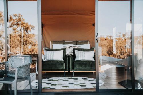 a room with a bed and chairs on a porch at Wildnest Farmstay in Capertee