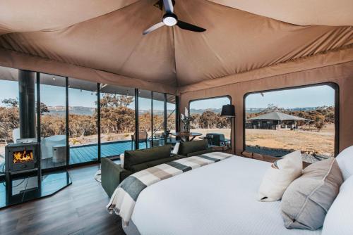 a bedroom in a safari tent with a bed and a fireplace at Wildnest Farmstay in Capertee