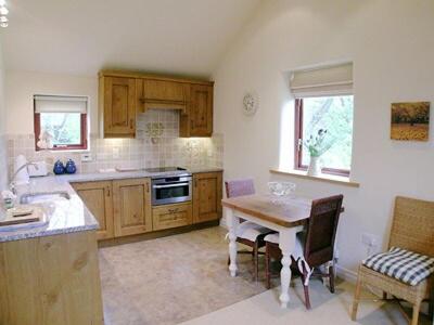 a kitchen with a table and a sink and a stove at Owl Cotes Cottage in Cowling