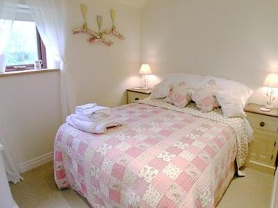 a bedroom with a bed with a pink and white blanket at Owl Cotes Cottage in Cowling