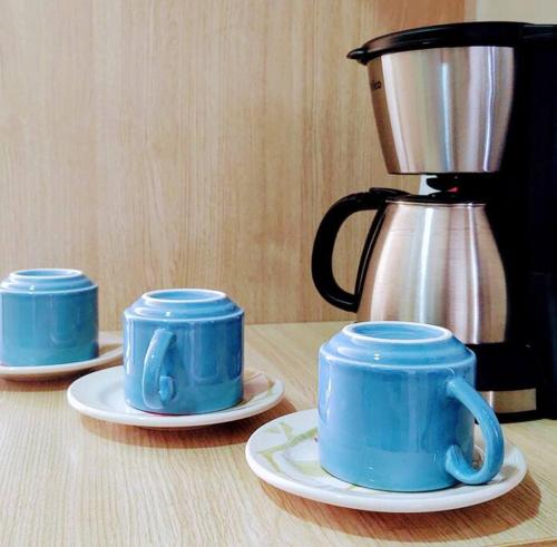 trois tasses et soucoupes bleues sur une table à côté d'un mixeur dans l'établissement Sinta-se em casa! Lindo Ap para você e sua família, à Manaus