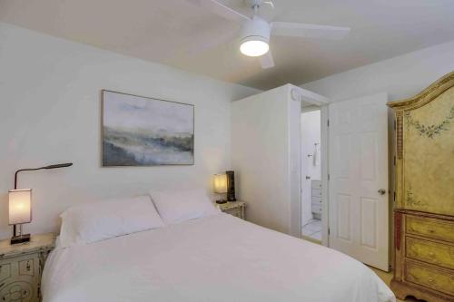 a white bedroom with a large bed and a dresser at Oceanbreeze - newly remodeled delightful oasis in the heart of Mission Beach, sleeps 6 in San Diego