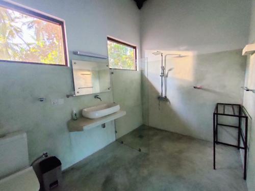 ein Bad mit einem Waschbecken, einer Leiter und einem Fenster in der Unterkunft Mawella Cove in Tangalle