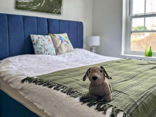 Apartment 7-uk42738 في وايتستابل: كلب محشو يجلس على رأس سرير