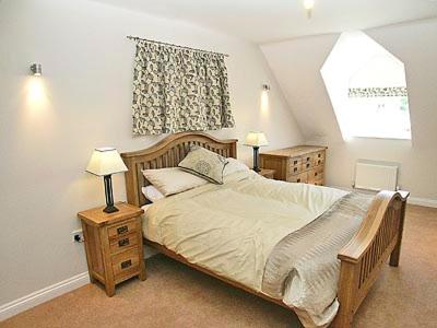 a bedroom with a bed and two night stands and a window at The Farmhouse in Cromer