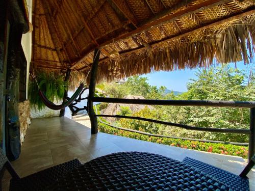 a view from a thatched room with a bench and a window at Quetzal Dorado Eco-Lodge by Mareygua in El Zaino