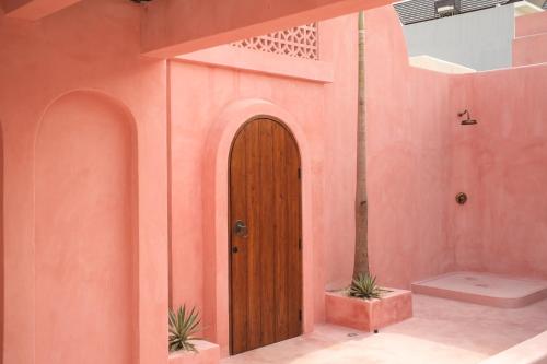 a room with a wooden door in a pink wall at Villa Ella June in Canggu