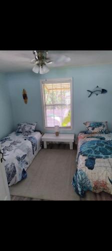 海濱公園的住宿－The Little Yellow Beach House，一间卧室设有两张床和窗户。