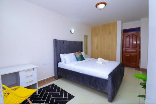 a bedroom with a bed with a desk and a yellow chair at Garden estate 1 bedroom furnished apartment in Nairobi