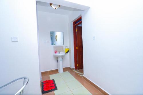 a white bathroom with a sink and a mirror at Garden estate 1 bedroom furnished apartment in Nairobi