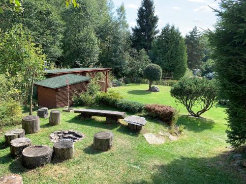 a garden with a bench and logs in the grass at Chata Sofie in Dolní Moravice