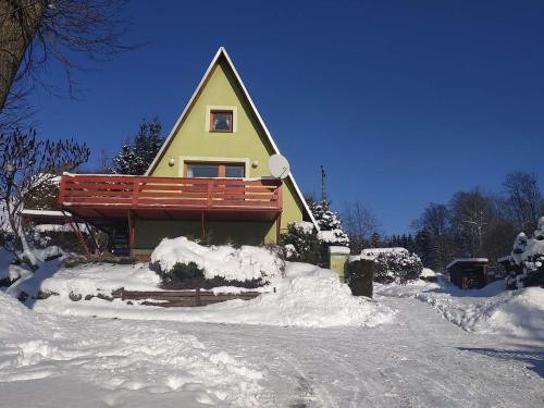 a yellow house with a red deck in the snow at Chata Sofie in Dolní Moravice