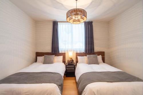 dwa łóżka w pokoju z oknem w obiekcie SAKURA house Marine w mieście Ito