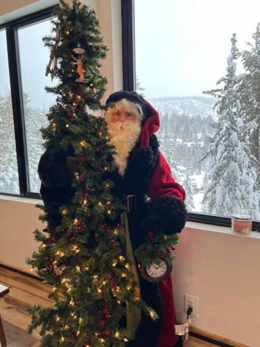 a santa claus standing next to a christmas tree at Gondola Chalet -New Luxury 5 Bdrm Condo @ Canyon Lodge, Steam Room in Mammoth Lakes
