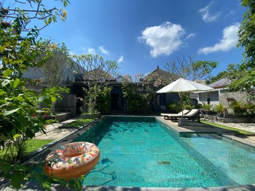 a swimming pool with a float in front of a house at Ashana Hotel in Uluwatu