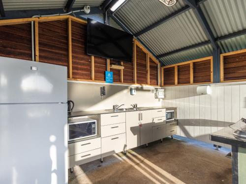 a kitchen with a white refrigerator and wooden cabinets at NRMA Port Campbell Holiday Park in Port Campbell