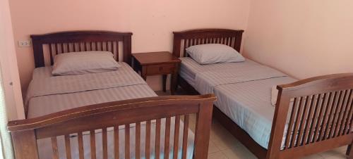 two twin beds in a room with two tables at Moon Travel Phangan in Ban Nua