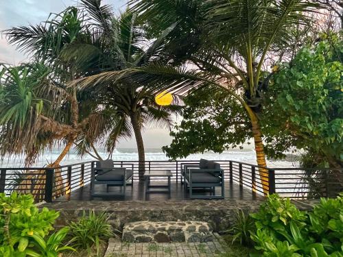 a patio with chairs and palm trees on the beach at Elysium in Unawatuna