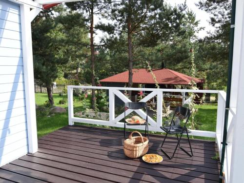 a deck with a white fence and a chair and a grill at Holiday Home near Lake Mausz with Sauna in Kłodno
