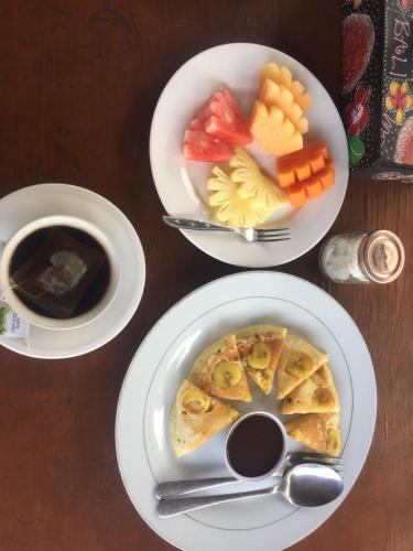 une table avec trois assiettes de nourriture et une tasse de café dans l'établissement Kenari Diwang, à Ubud