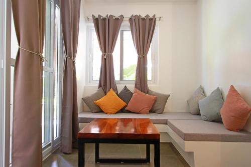 a couch with pillows and a table in front of a window at Bathala Resort in Panglao