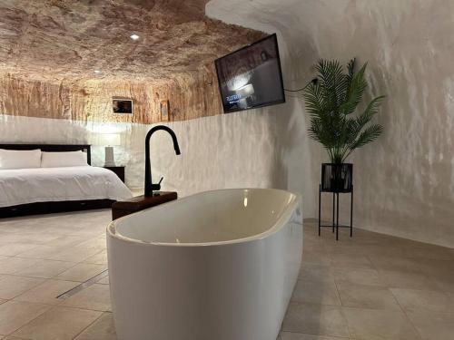 a bath tub in a bedroom with a bed at Cozy Cave Coober Pedy in Coober Pedy