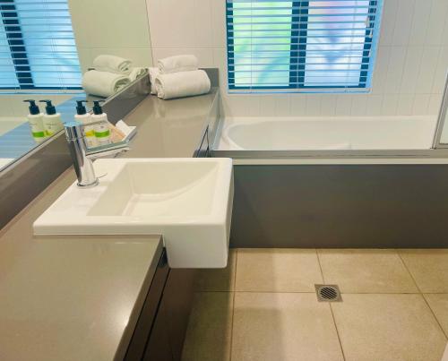 a bathroom with a sink and a bath tub at Lagoon Swimout Absolute Pool Front - Slice of Paradise - Sea Temple Pt Douglas in Port Douglas