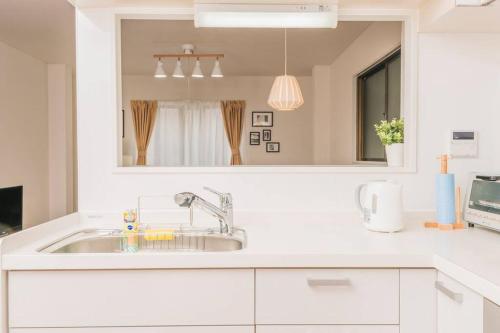 a white kitchen with a sink and a mirror at Osaka Viewing House丨4min-st aion丨Near Namba, Umeda liubj4 in Osaka
