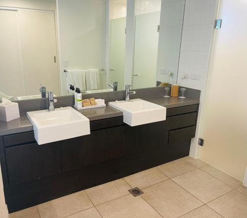a bathroom with two sinks and a large mirror at Paradise Escape - Poolside Ground Floor - Sea Temple Resort and Spa in Port Douglas