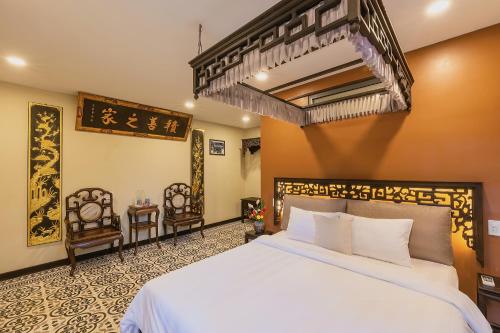 1 Schlafzimmer mit einem großen weißen Bett und 2 Stühlen in der Unterkunft HueNam Residence in Hue