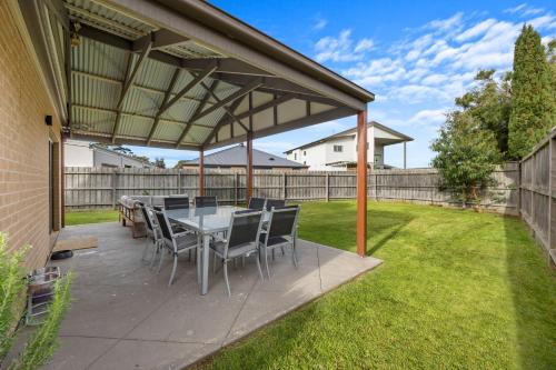 a patio with a table and chairs under a roof at Paperbark Escape in Inverloch