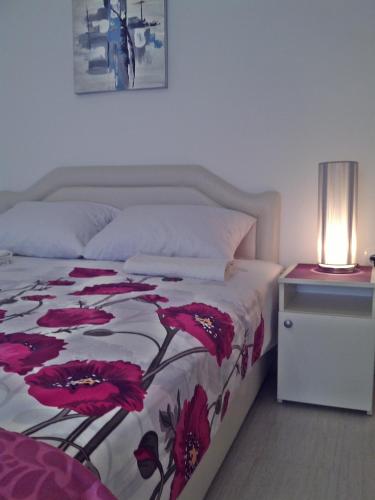 a bedroom with a bed with a red flower blanket at Kotor Kelly Apartments in Kotor