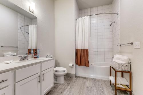 Baño blanco con aseo y lavamanos en Lush Downtown Condo on RiverWalk #1100 en San Antonio