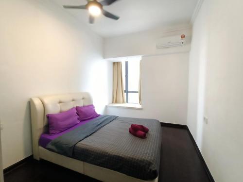 新山的住宿－R&F princess cove family premium suites，一间卧室配有一张带紫色枕头的床和吊扇。