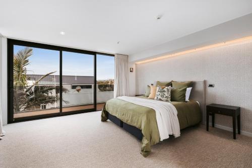 a bedroom with a large bed and a large window at Luxury in Paradise - Sea views and Beach in Mount Maunganui